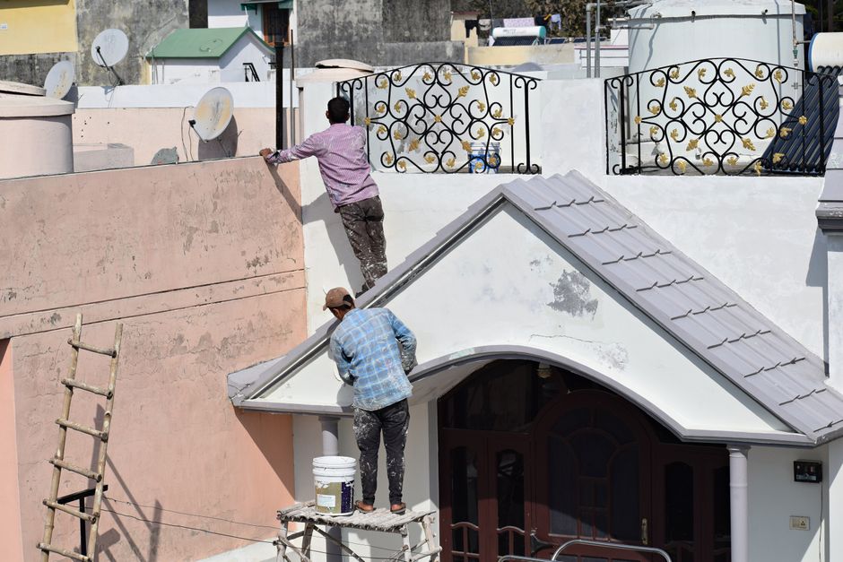 Two workers painting a building during a renovation.