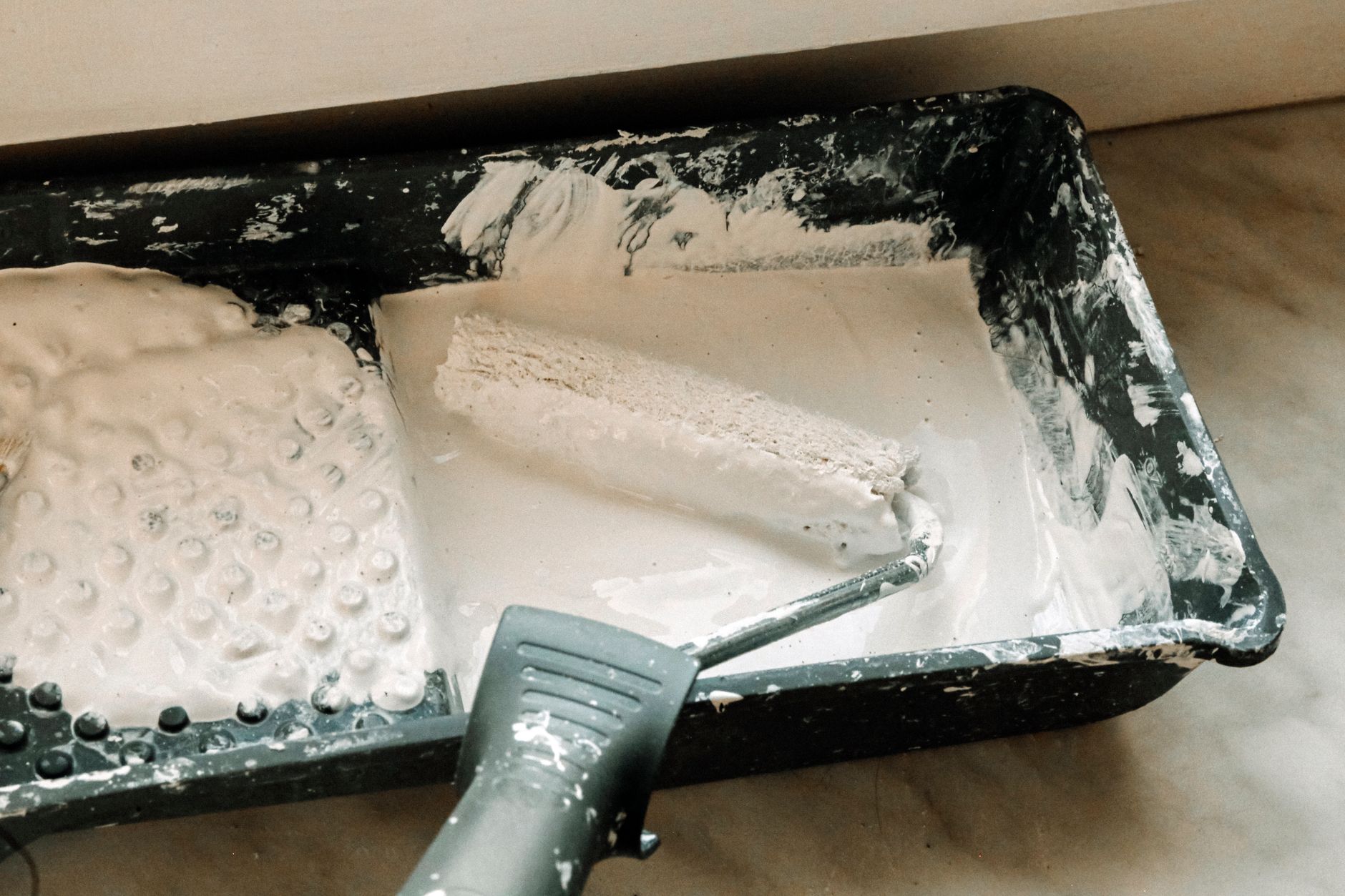 A paint roller dipped in white paint in a plastic tray, ideal for home renovation projects in Long Beach, CA
