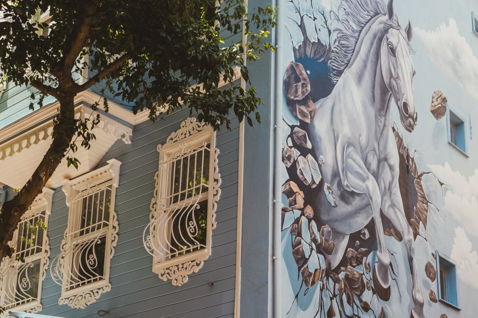 Painted mural on a blue house wall with decorated windows.